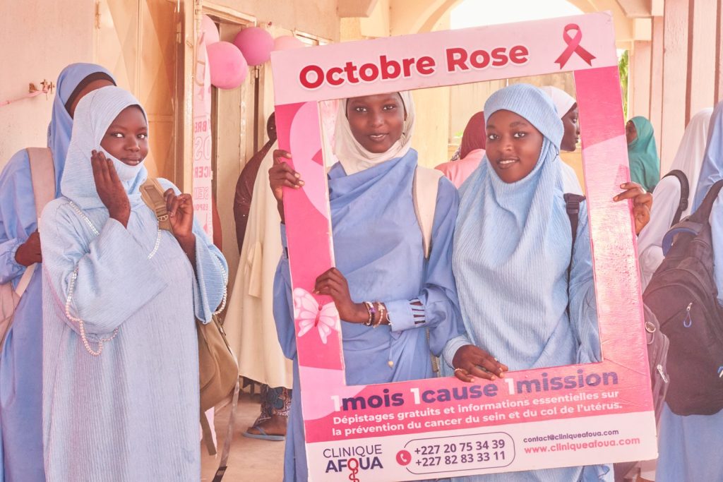 Jeunes filles posant dans le cadre photo Octobre Rose de la Clinique Afoua à Liboré