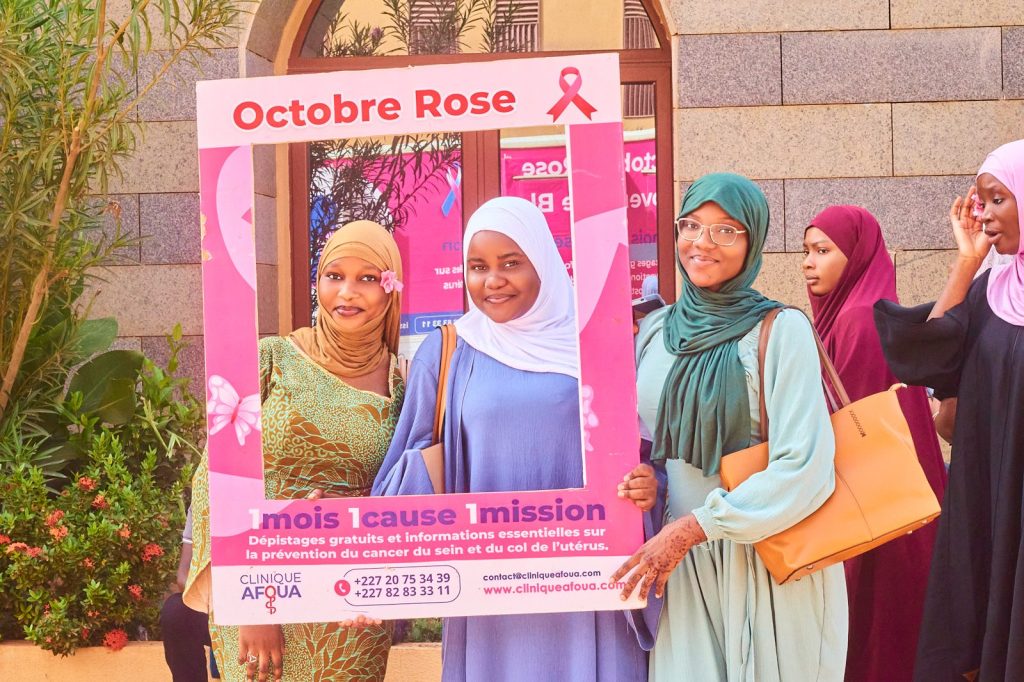 Étudiantes posant dans le cadre photo Octobre Rose de la Clinique Afoua