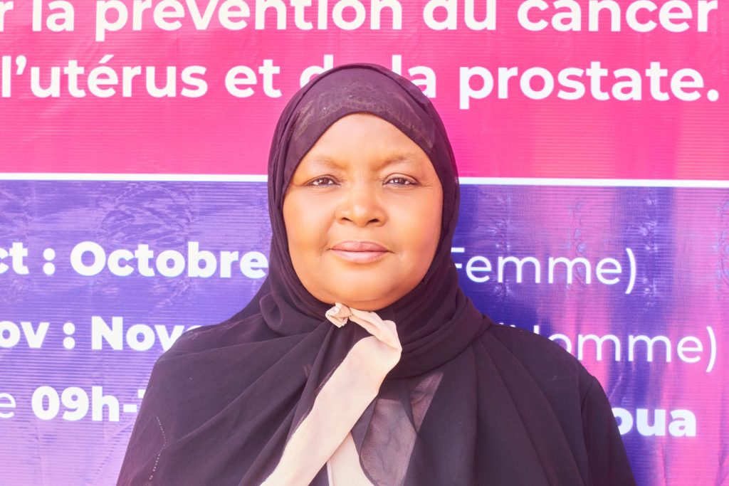 Portrait d’une participante de la CONGAFEN devant l’affiche de la campagne Octobre Rose